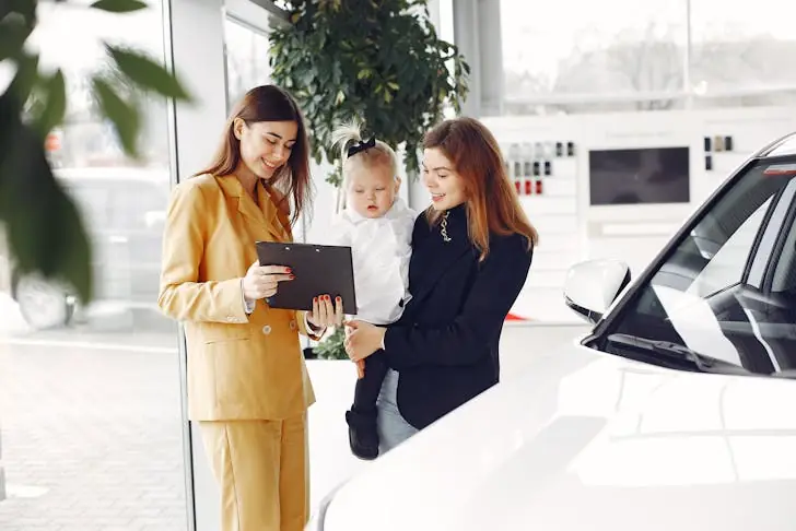 How do car salesman get paid - Image of car saleswoman showing contract to happy mother.